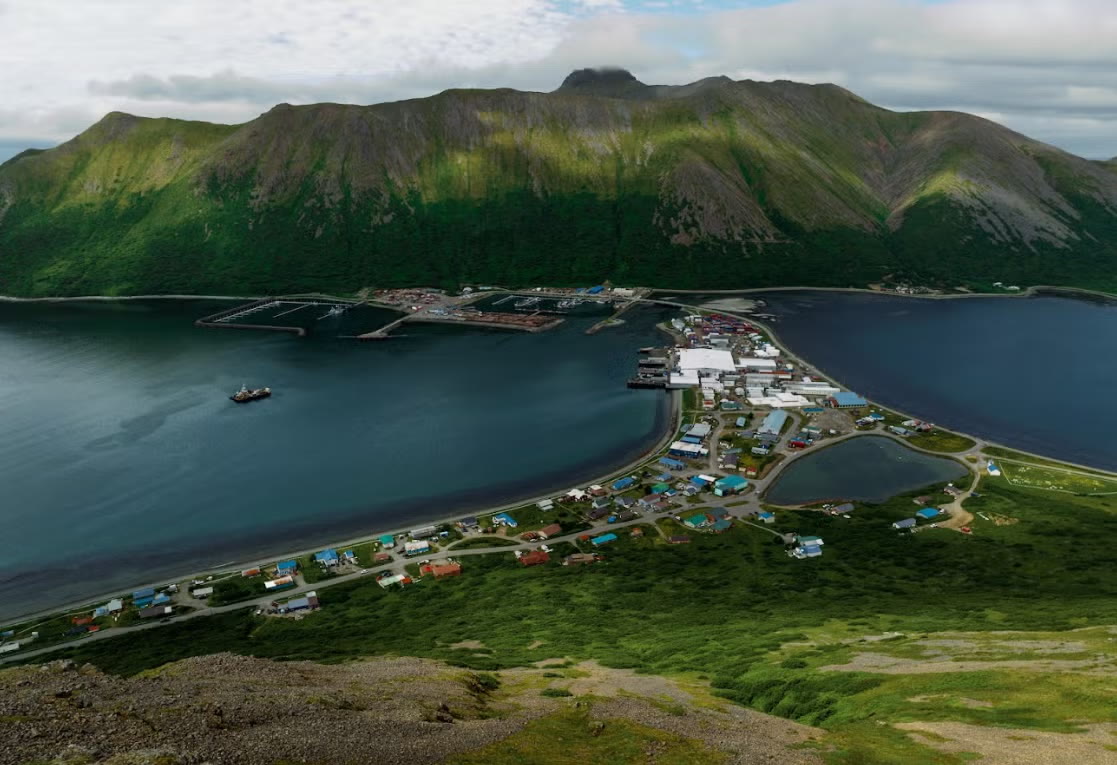 Panorama of King Cove, Alaska with a fishing vessel in the foreground