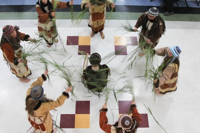 Aleut dancers in traditional regalia performing a dance in a circle