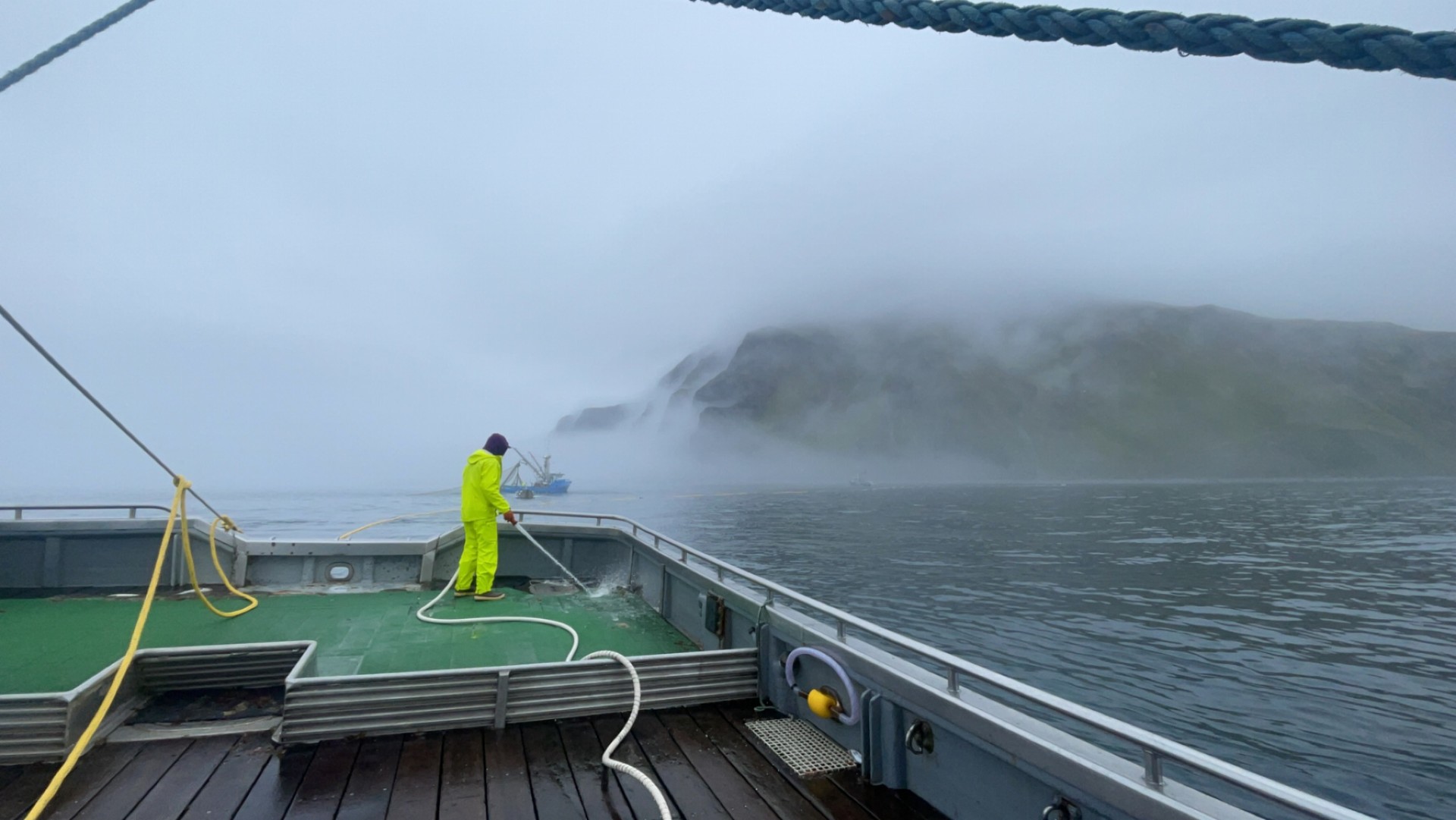 Crew spraying off the deck while holding open on a foggy day in Area M